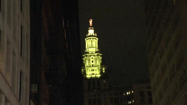 A New York City municipal building lit up in yellow. 