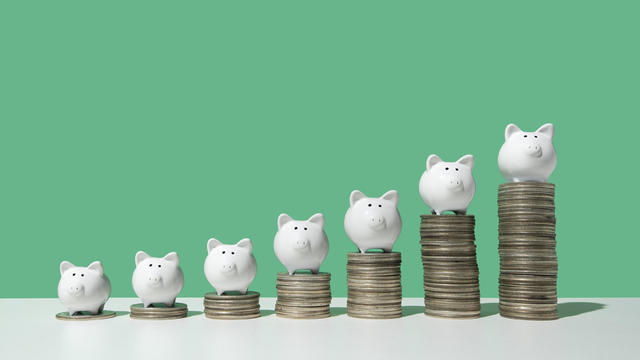 Little piggy banks on ascending stacks of coins 
